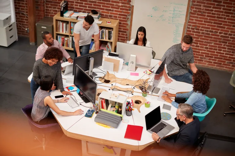 Colleagues discussing work around a shared table in an office