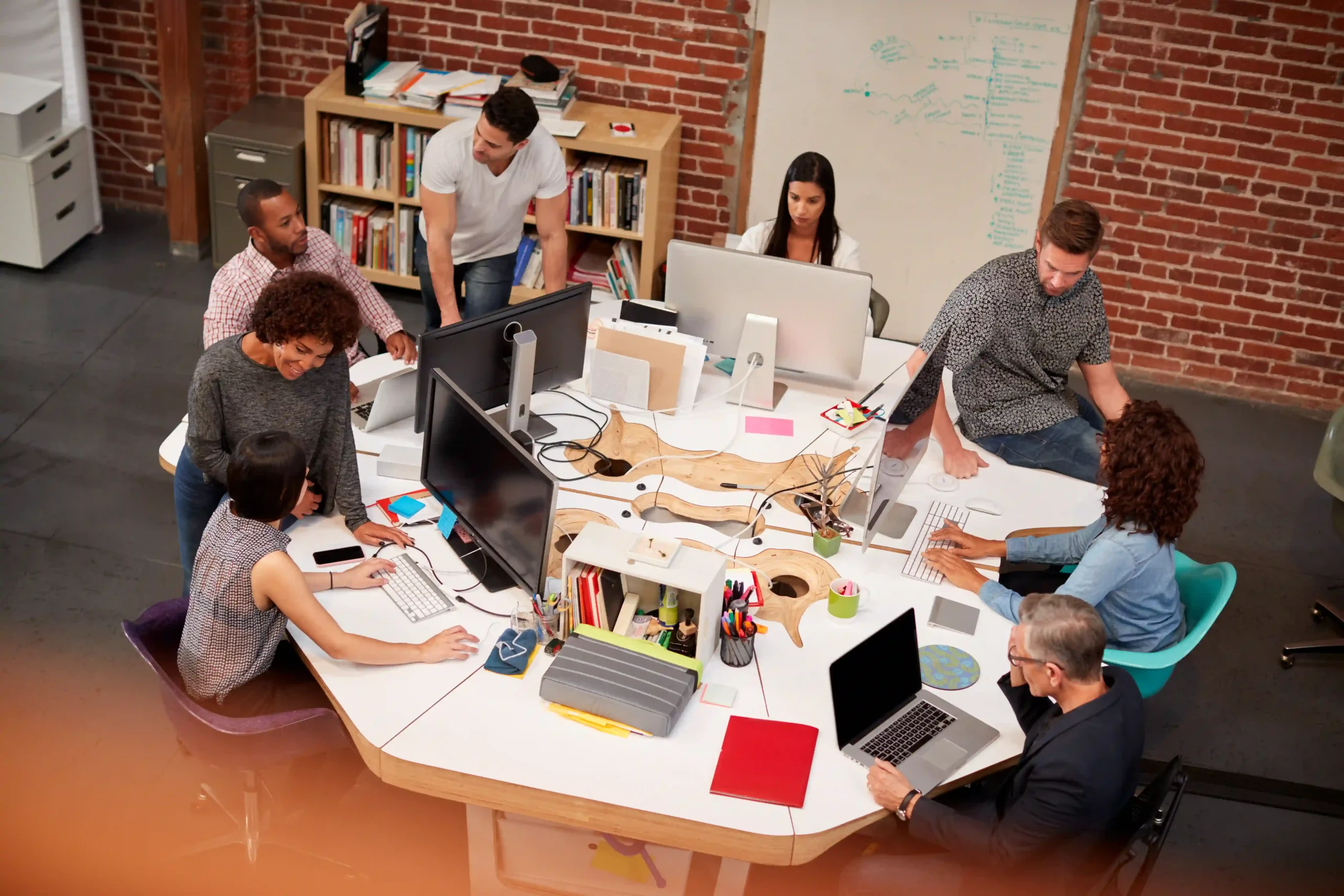 Colleagues discussing work around a shared table in an office